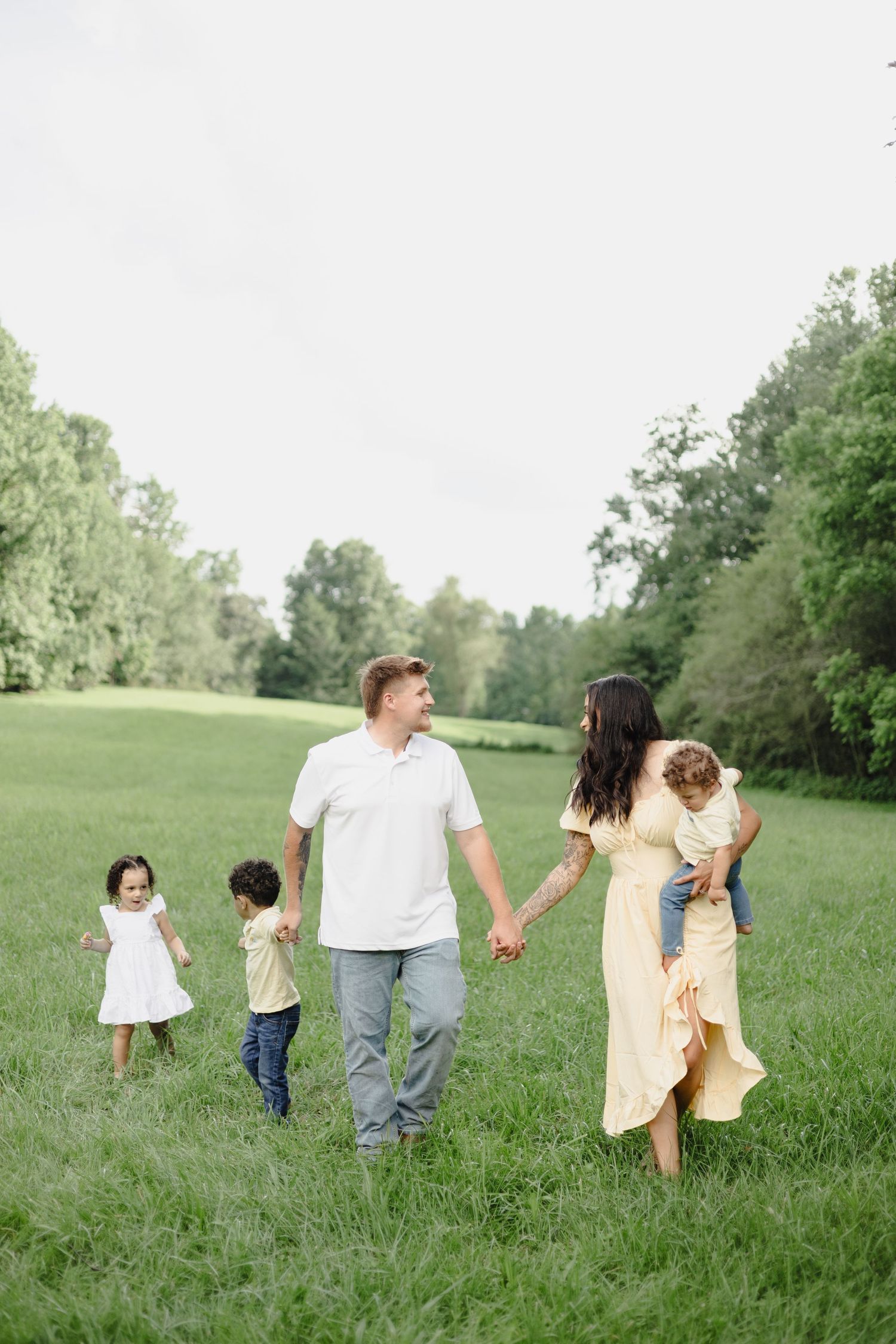 A group huddles together for a heartwarming moment by a serene pond in a wooded setting.