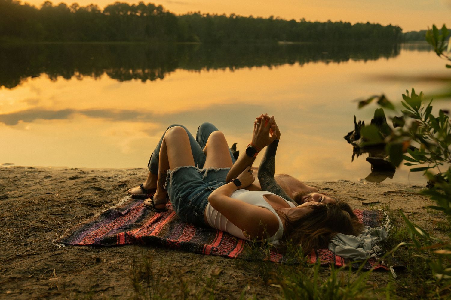 A tender moment shared between a couple on a wooden boardwalk surrounded by lush greenery.