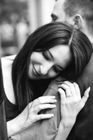 A sweet black and white portrait shows a tender embrace with a joyful smile between two people.
