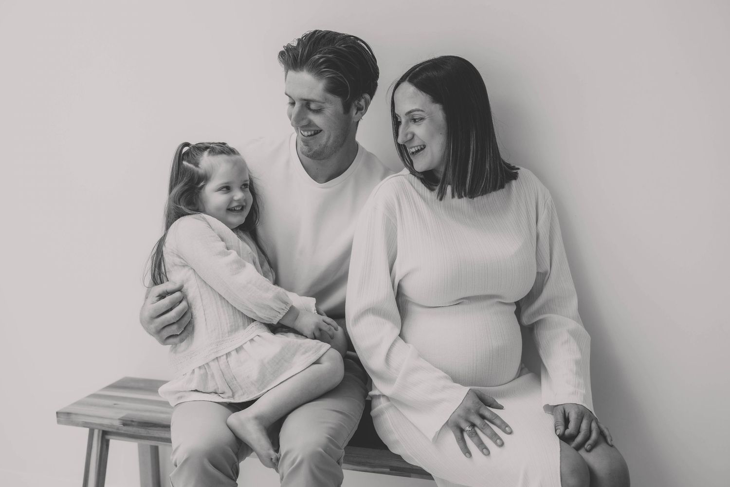 Intimate family portrait of parents and children sharing a tender moment on white background.