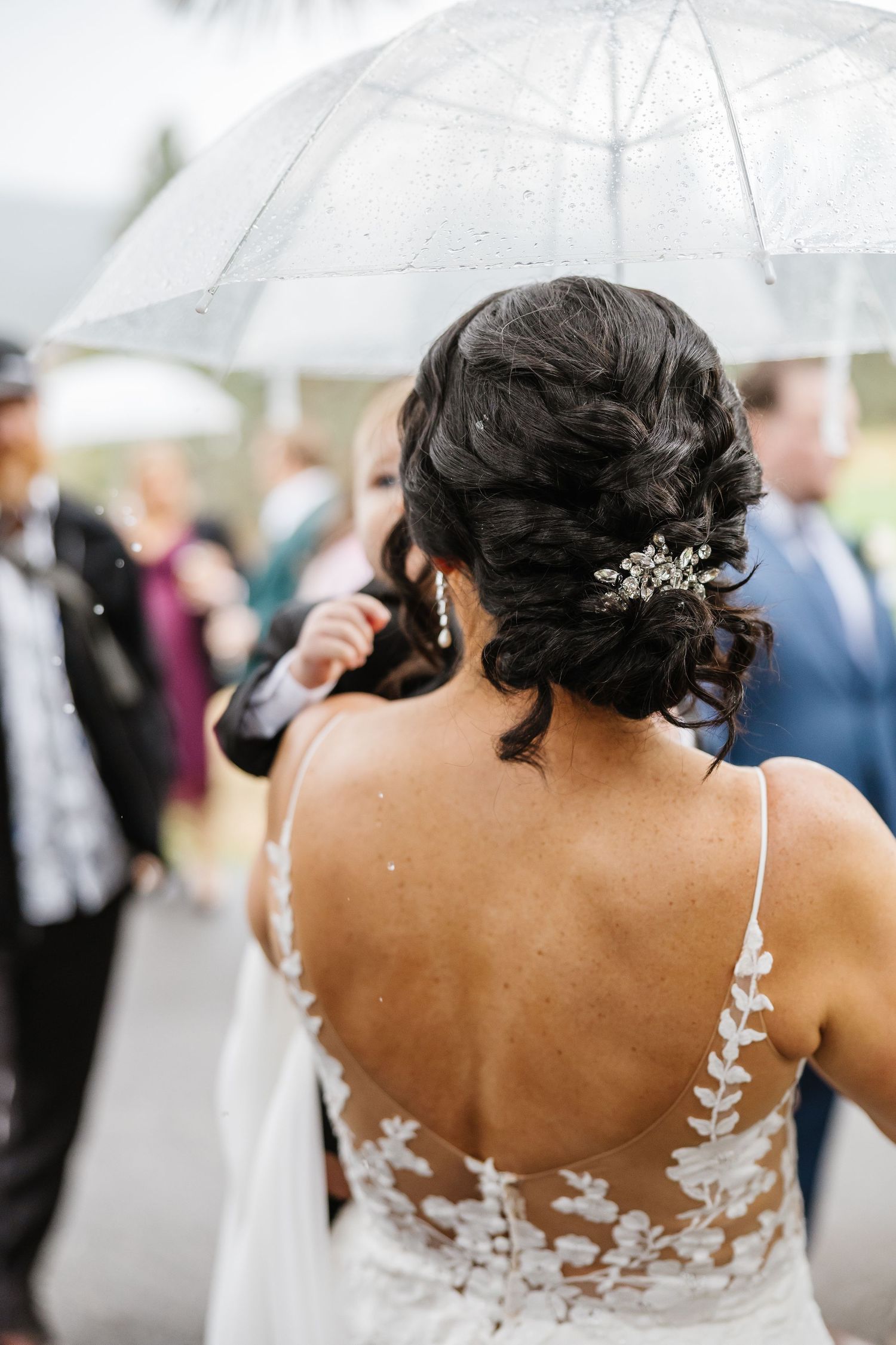 A close-up view of a bride's back showing intricate white lace details on her wedding dress with sheer elements.