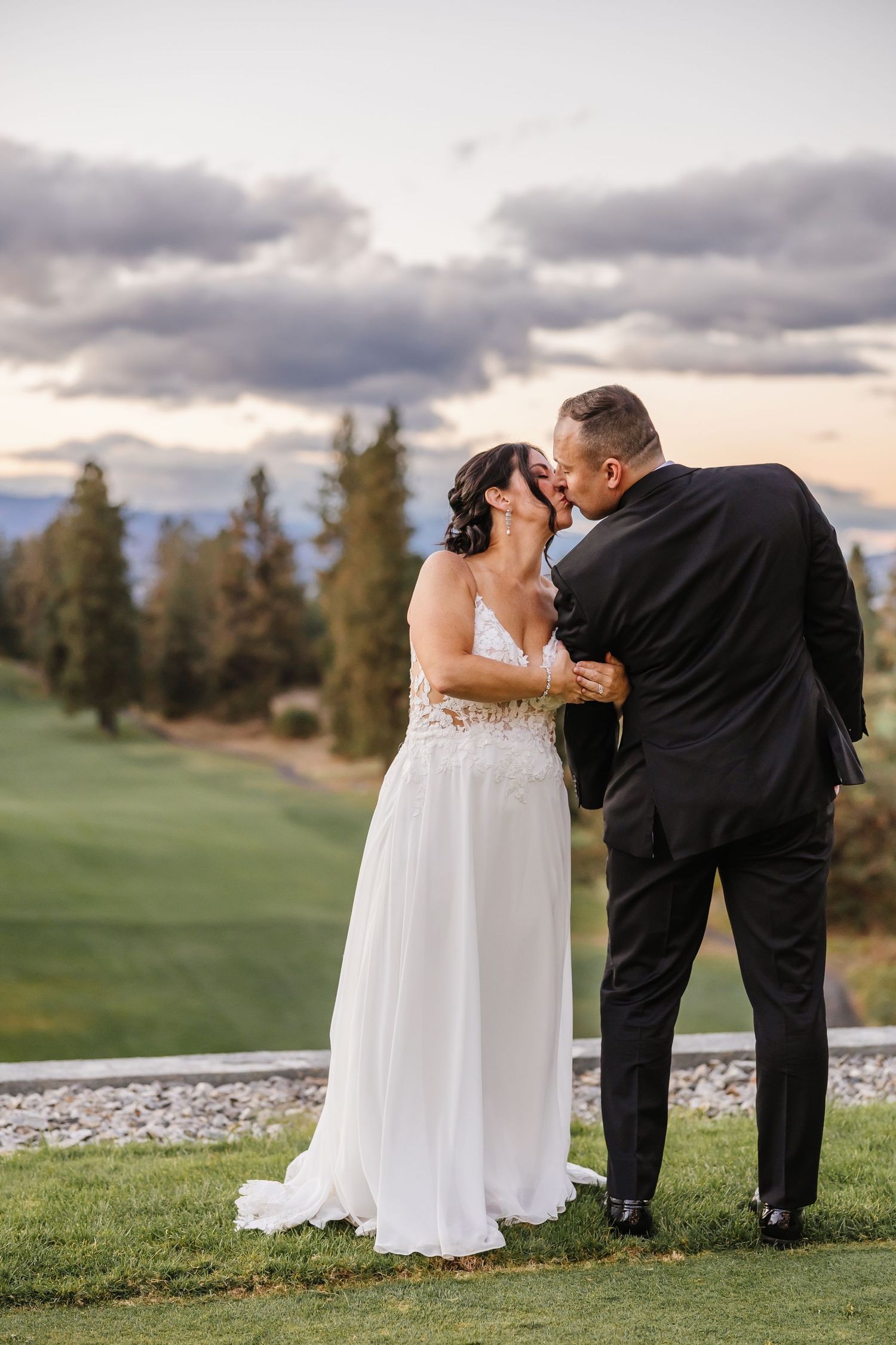 A romantic moment shared between newlyweds on a lush golf course at sunset.