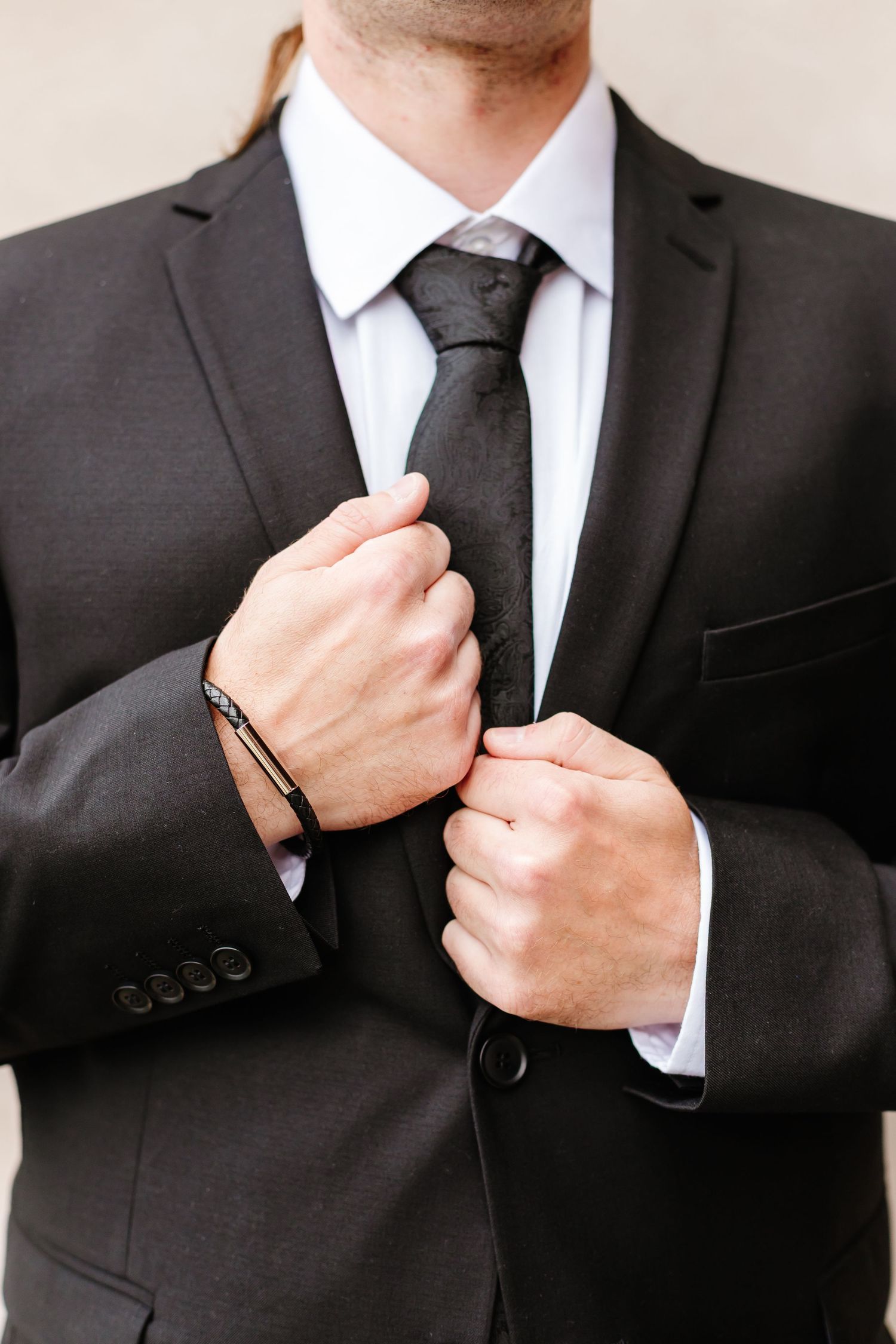 Close-up sequence showing man adjusting black suit tie and collar.
