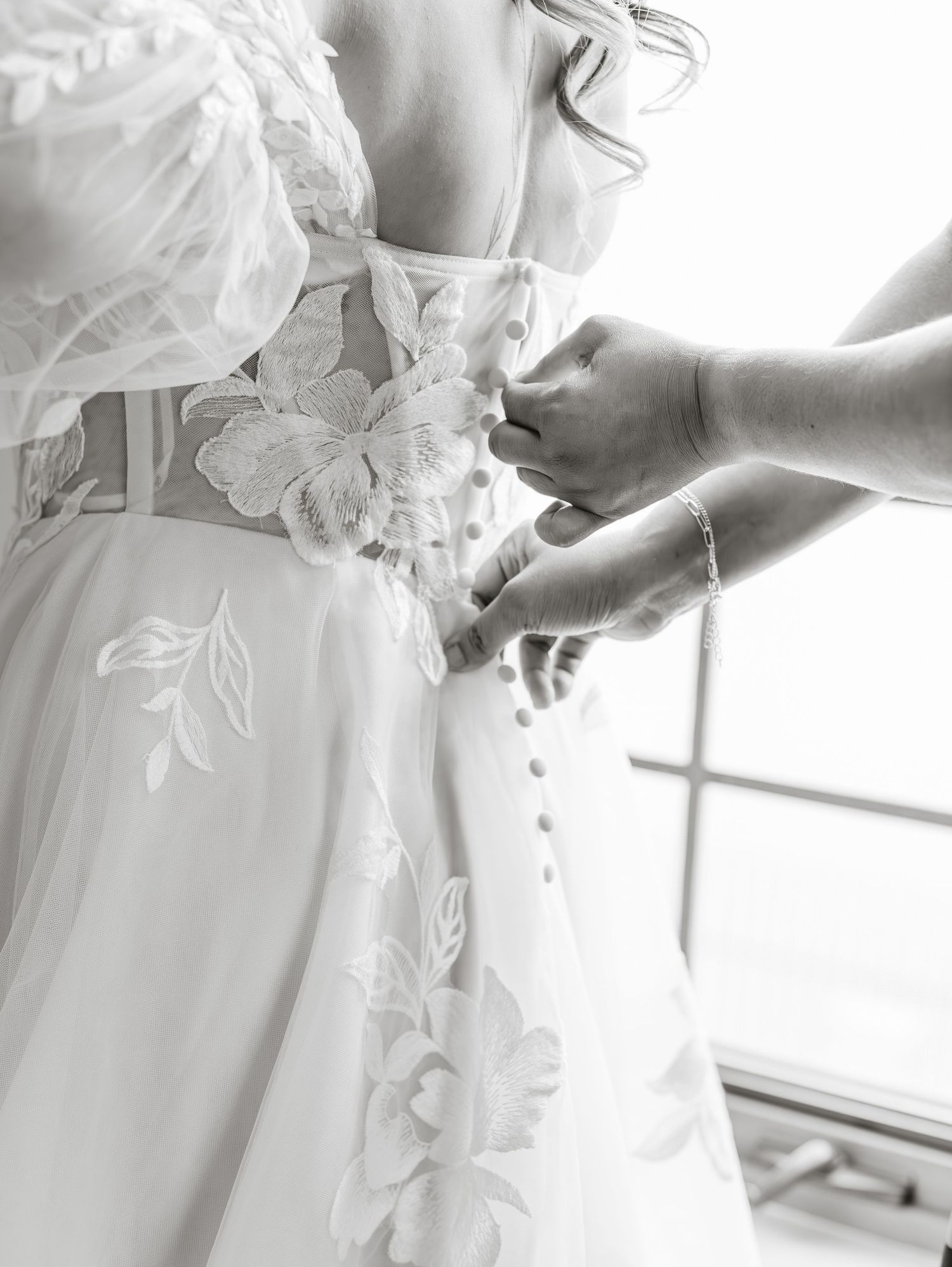 Close-up details of a white wedding dress with delicate lace and button details.