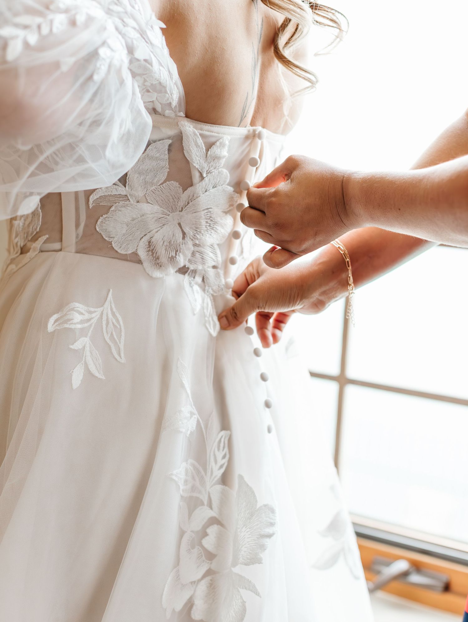 Close-up details of a white wedding dress with delicate floral appliques and lace embellishments.