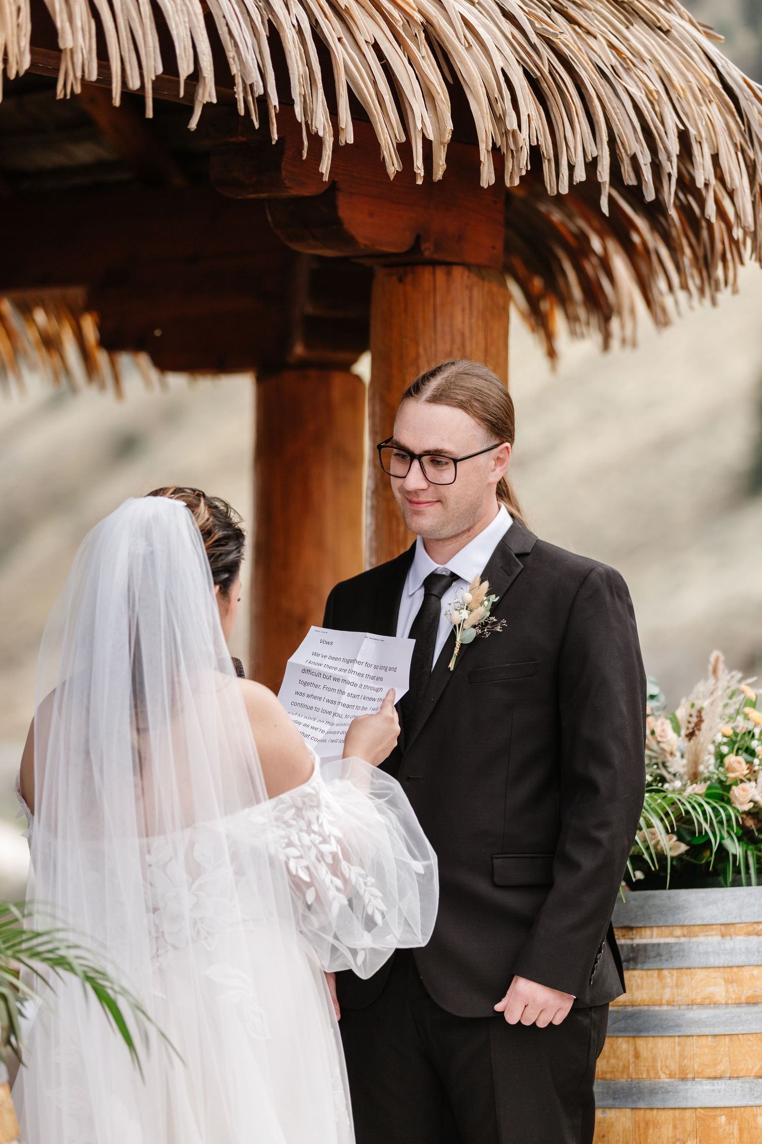 A touching first look moment between a couple under a thatched pavilion during their wedding ceremony.