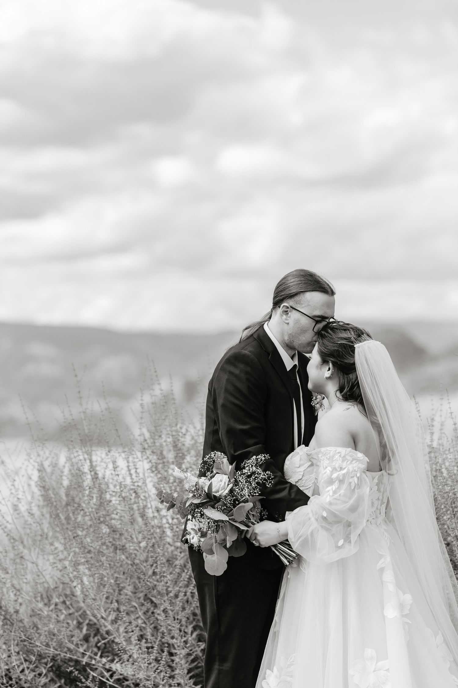 Black and white wedding portrait in a field of lavender with mountains in the background.