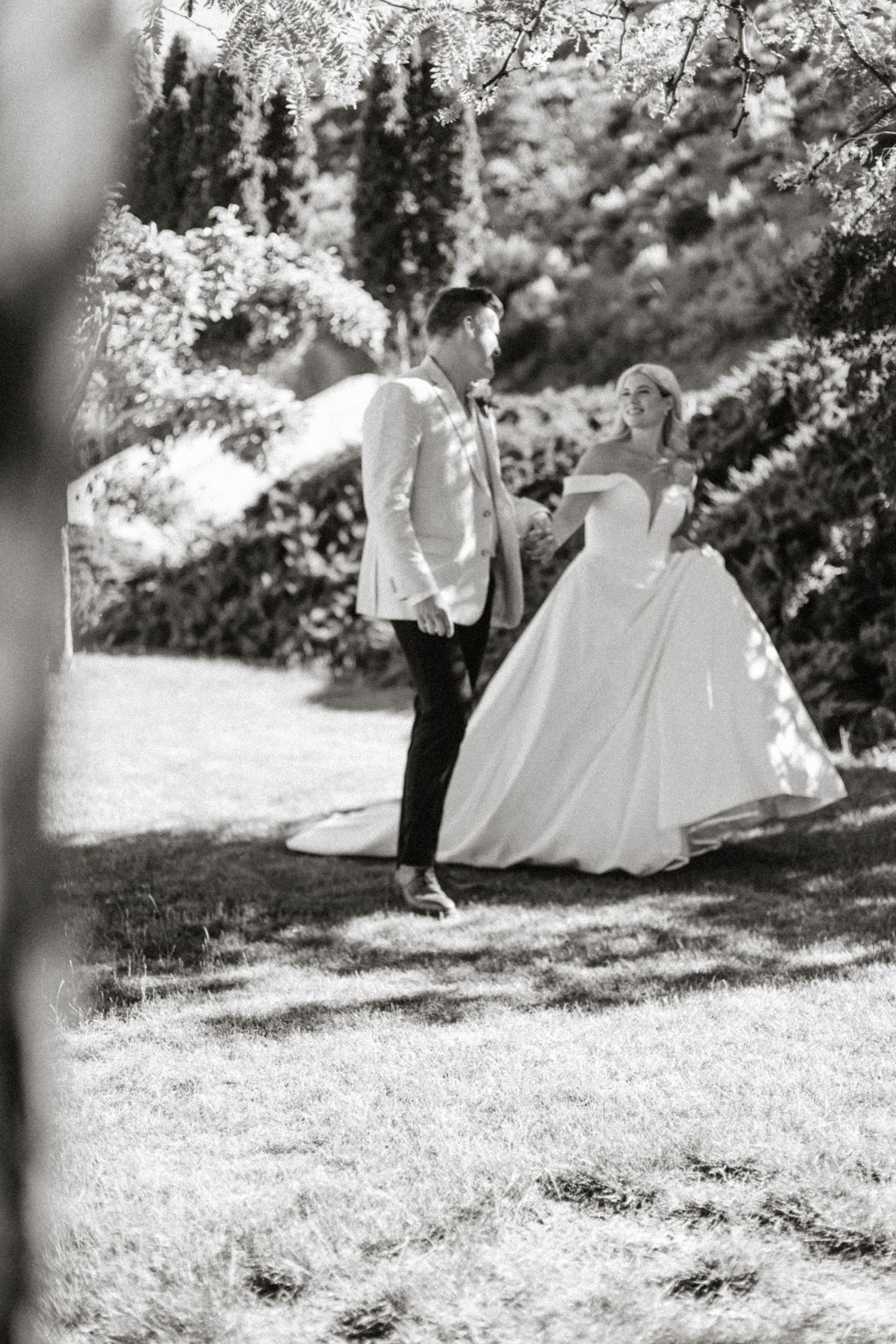 Black and white wedding photo of a couple sharing a romantic moment in a garden setting.