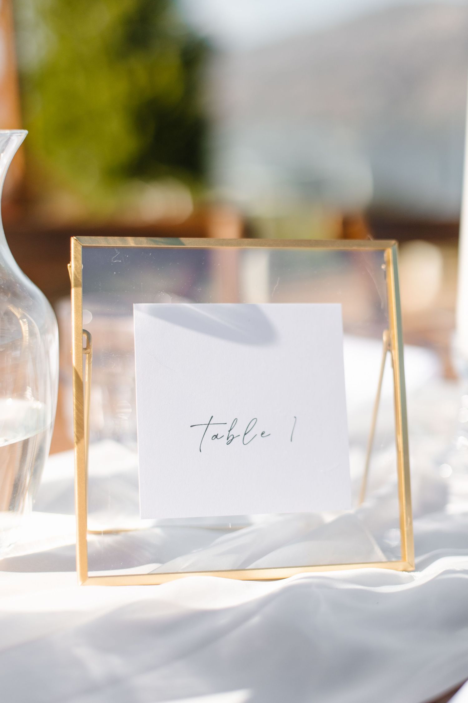 White table settings with name cards and gold accents create an elegant wedding reception display.