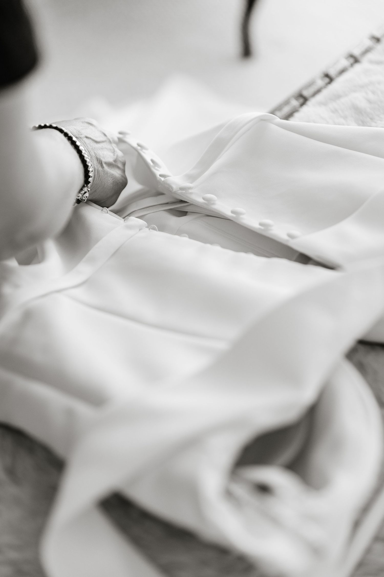 Close-up view of white fabric being sewn on a sewing machine with stitches visible along the seam.