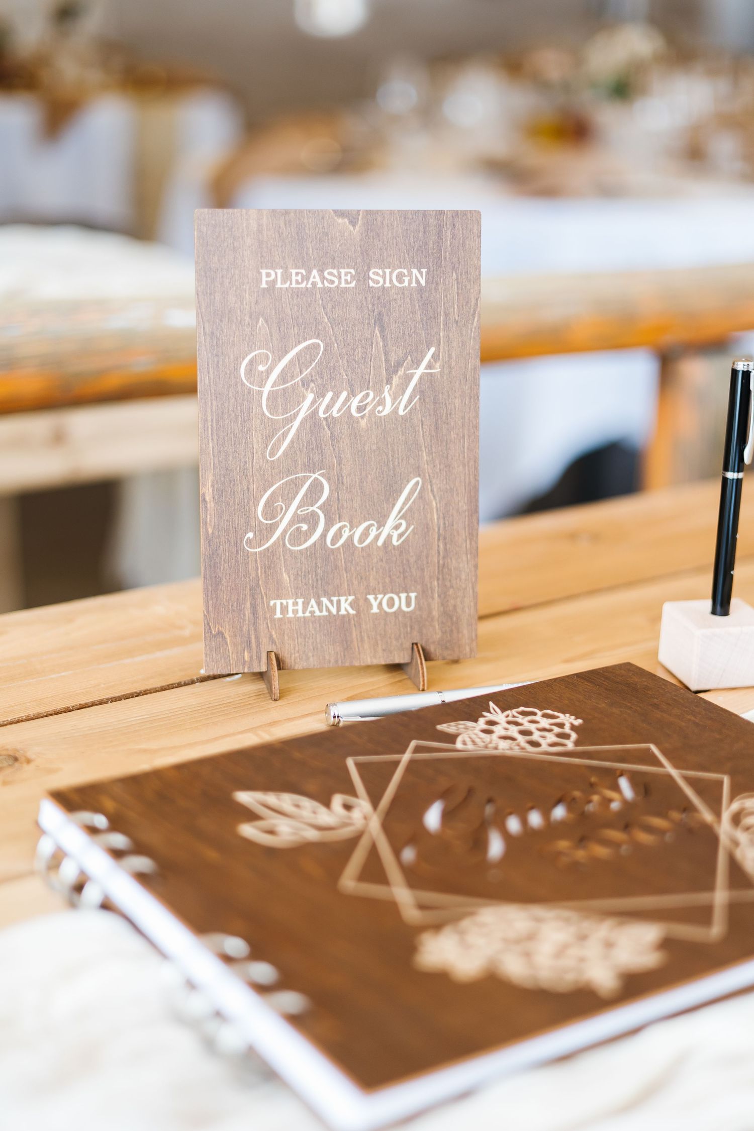 Rustic wooden wedding guest books and thank you signs displayed on a white tablecloth.