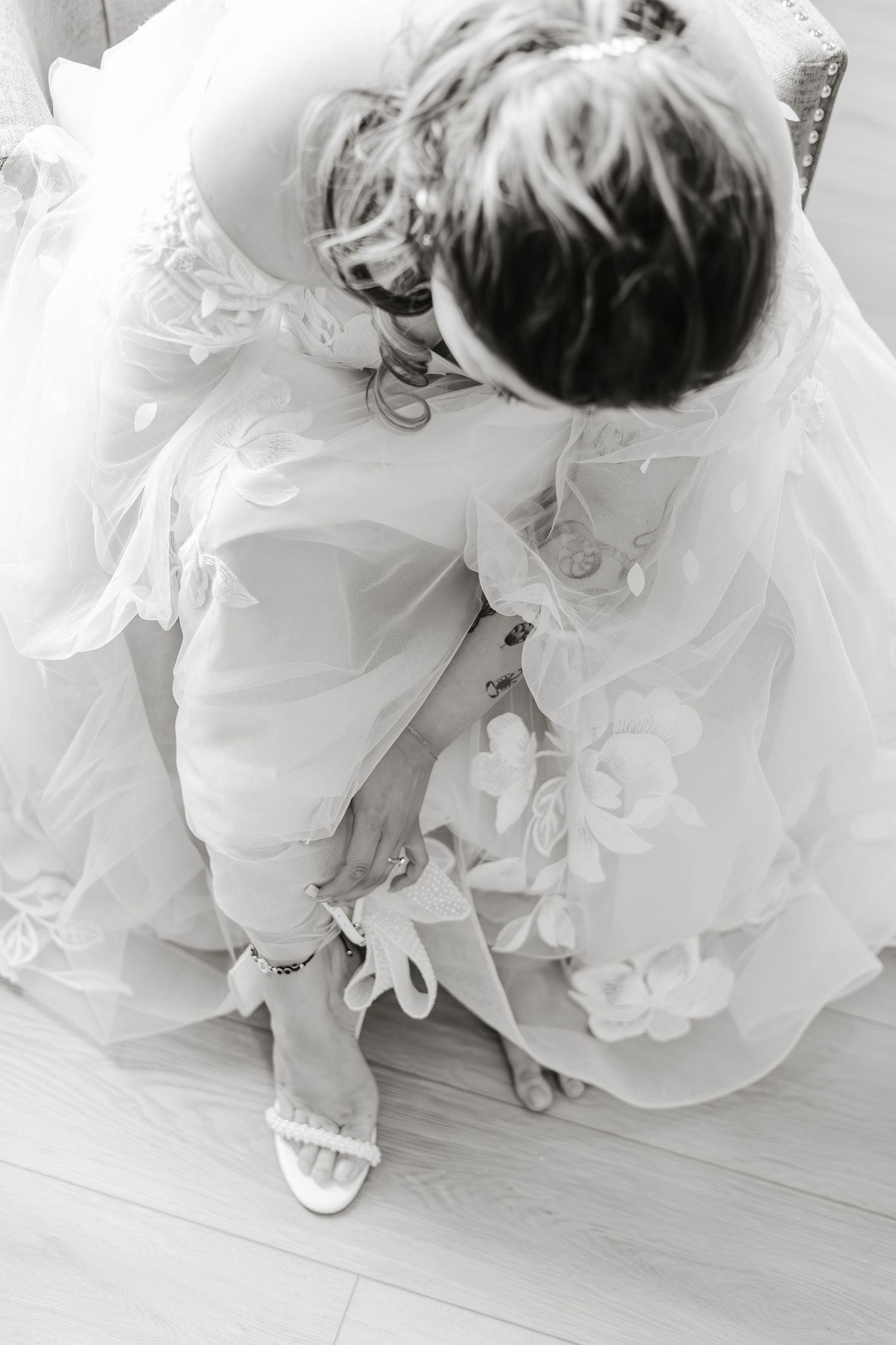 Close-up sequence of a bride's white wedding dress and shoes in black and white photography.