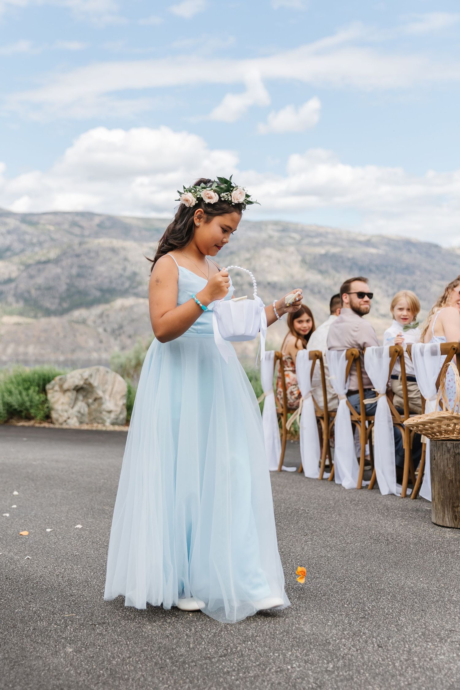 Young bridesmaids in light blue dresses walk down an outdoor path with mountains in the background.