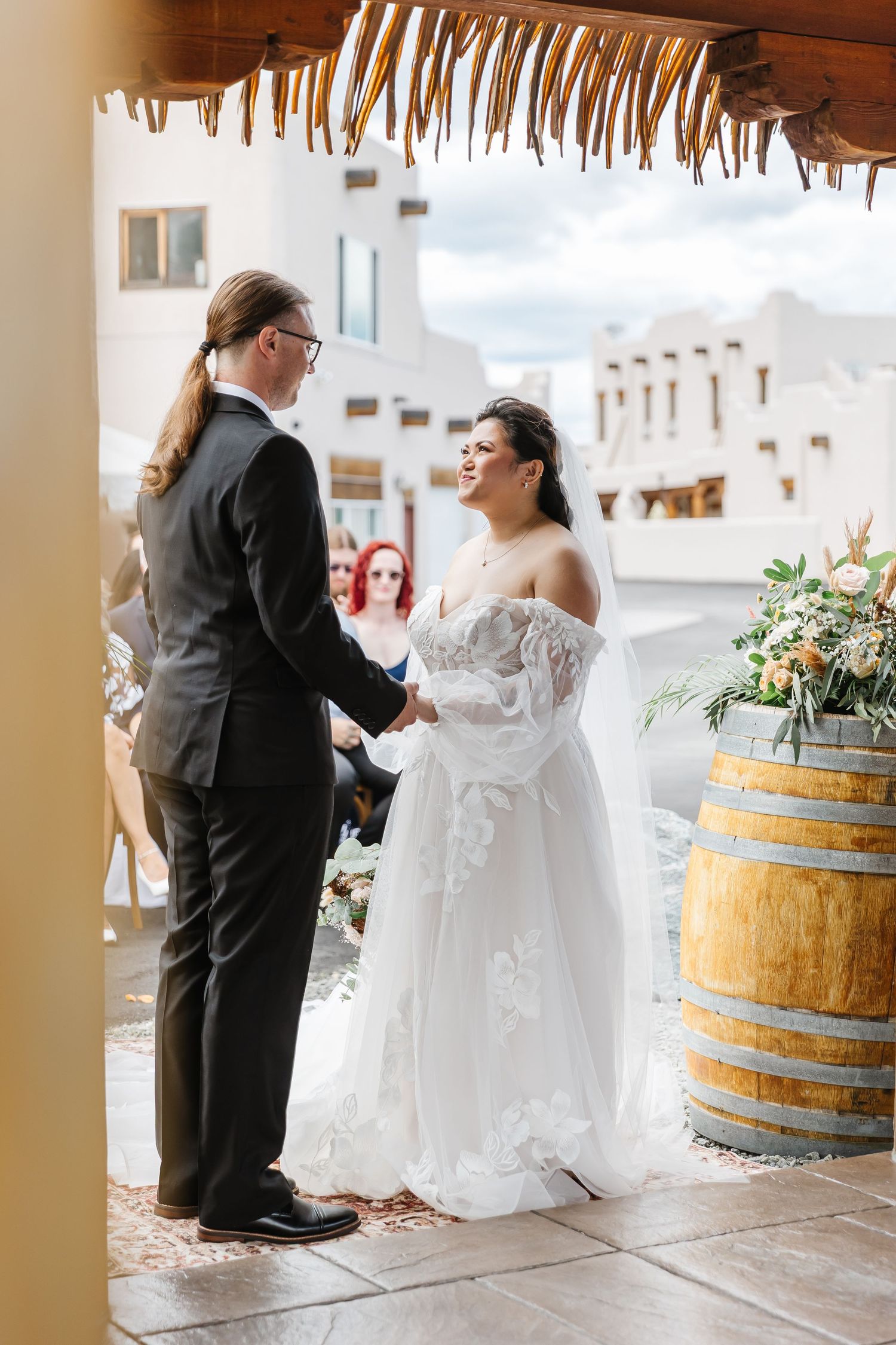 Wedding scene with rustic wooden barrels and decorative lighting in an indoor venue.