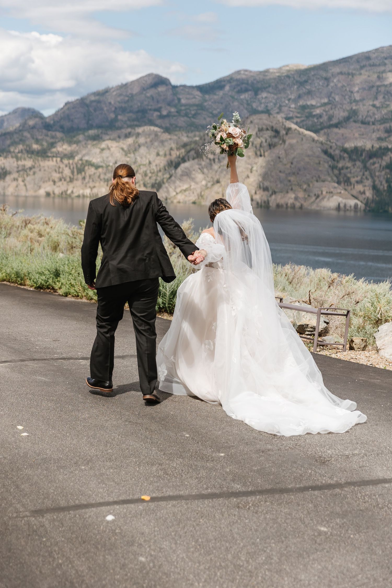 A couple poses for wedding photos with scenic mountain lake views in the background.