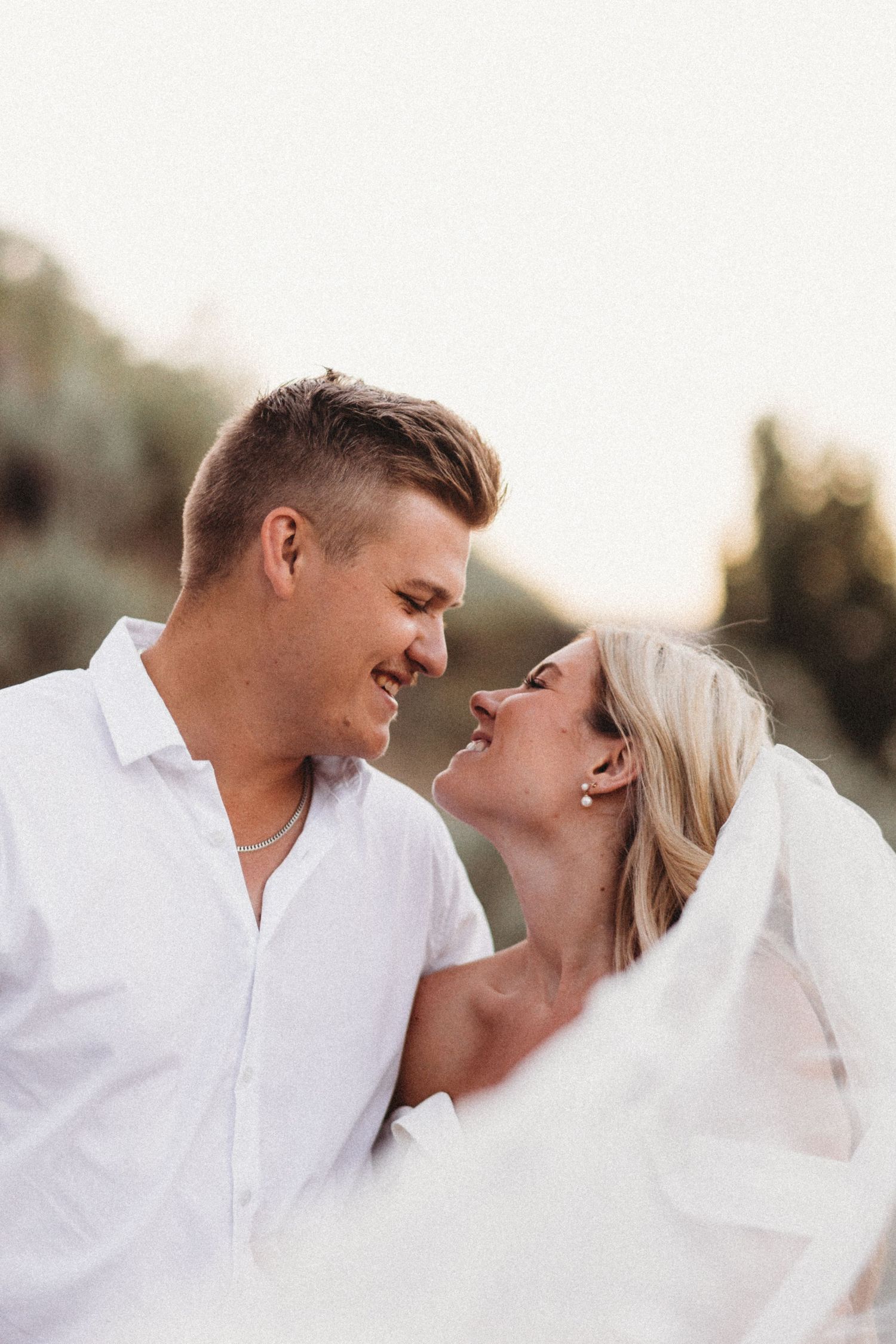 A romantic moment captured between newlyweds against a soft sunset background.