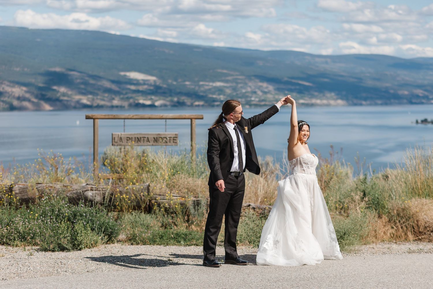 Wedding photo session with scenic mountain lake backdrop on a sunny day.
