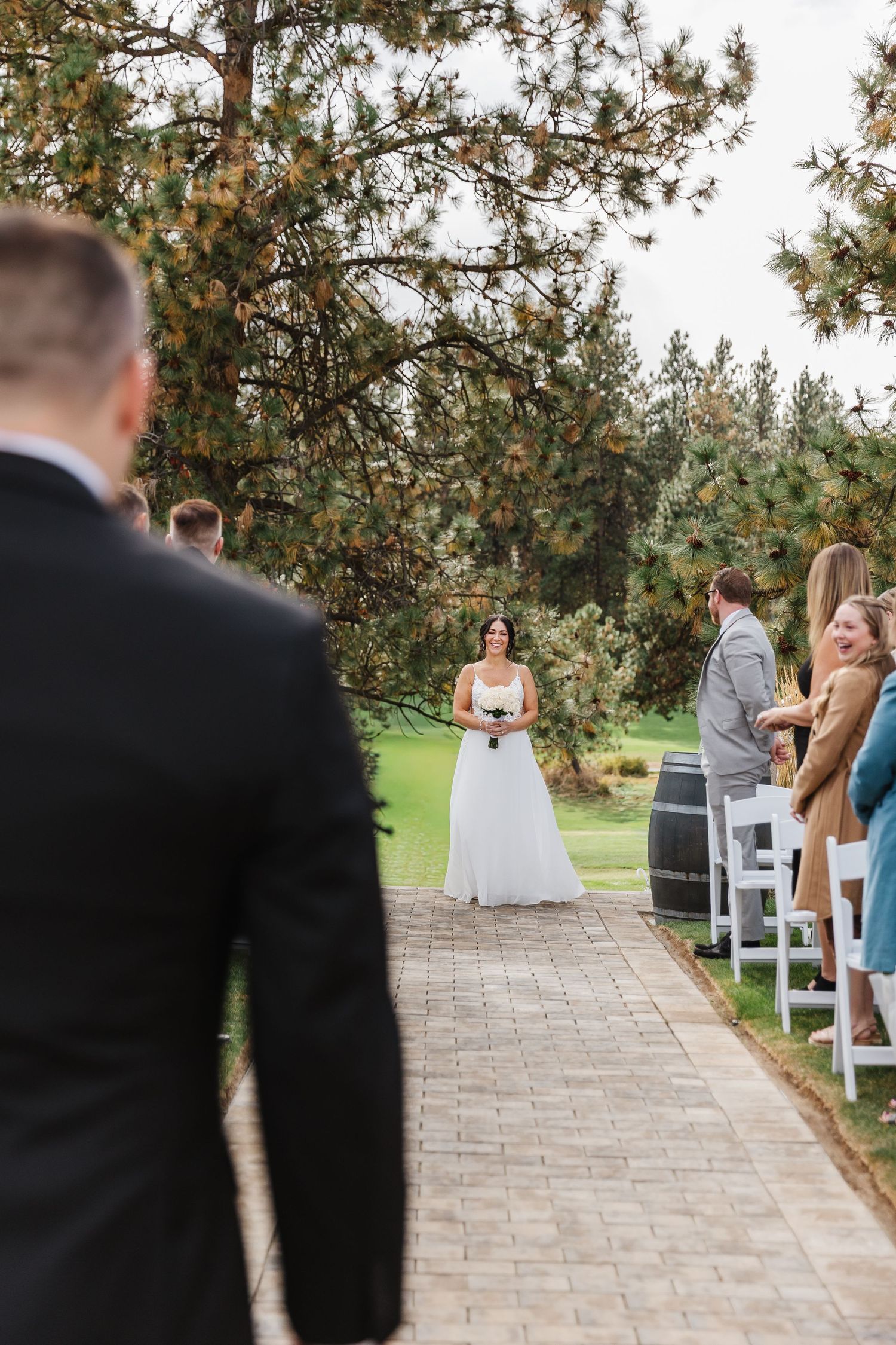 Outdoor wedding ceremony setup showing a stone path leading to an altar area surrounded by evergreen trees.