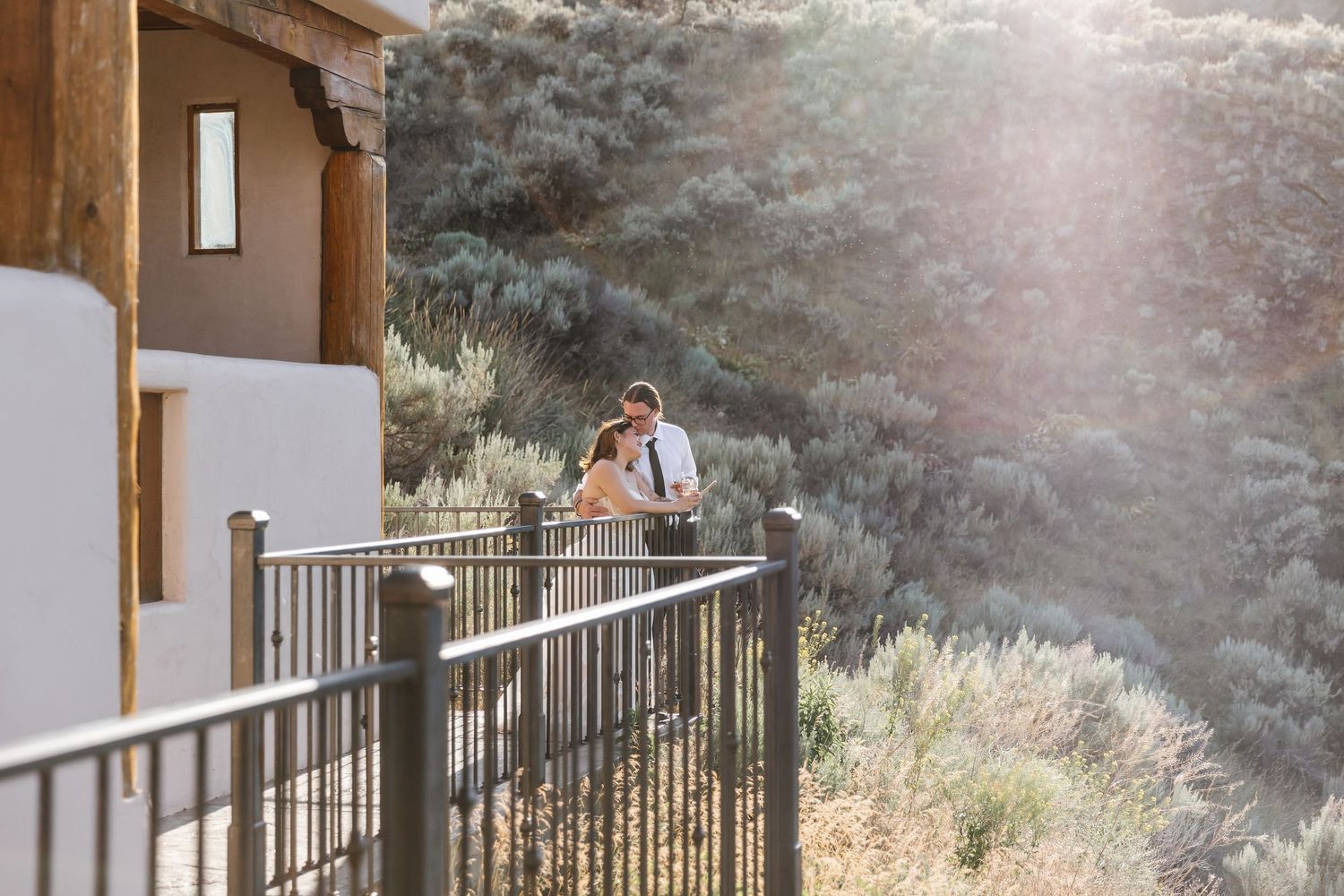 Romantic couple on a balcony overlooking mountain scenery at sunset.
