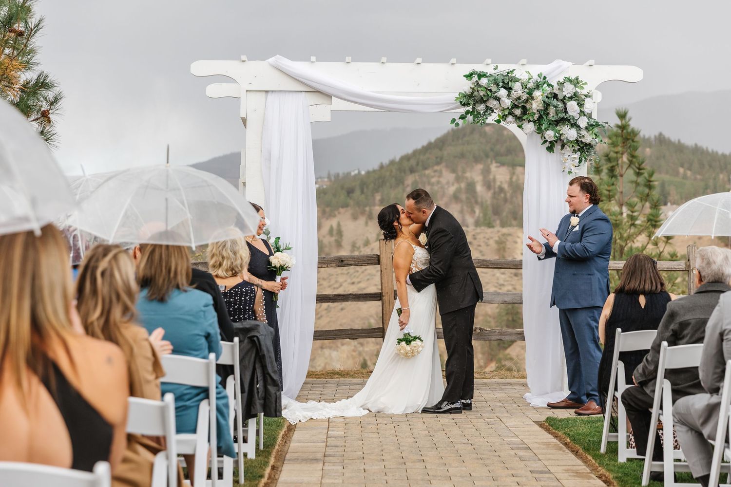 A romantic outdoor wedding ceremony in front of white drapes with mountain views in the background.