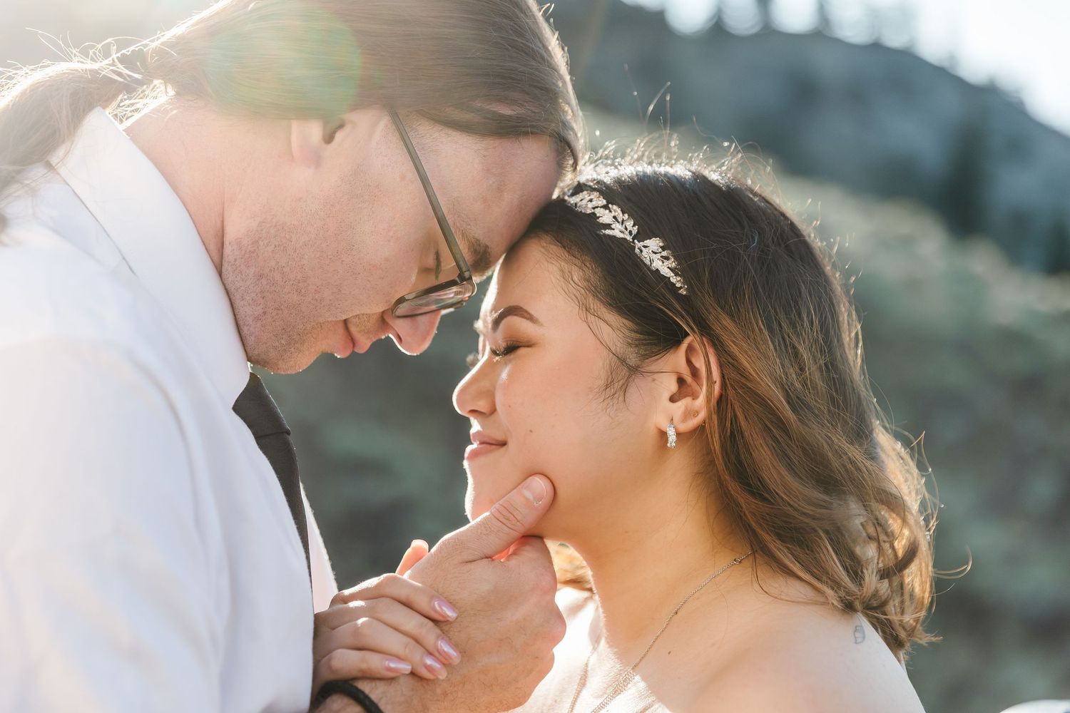 Intimate wedding portraits captured in golden sunlight against mountain backdrop.