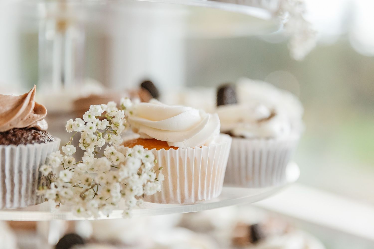 Elegant cupcakes decorated with pink frosting and delicate baby's breath flowers on a white dessert stand.