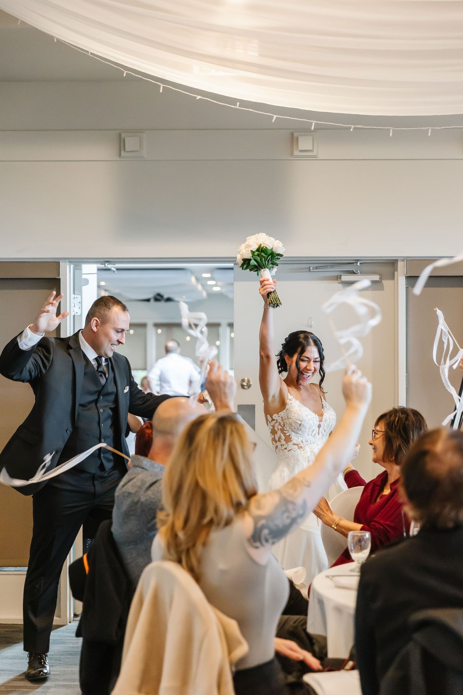 Wedding guests dance and celebrate with raised arms during a lively reception celebration.