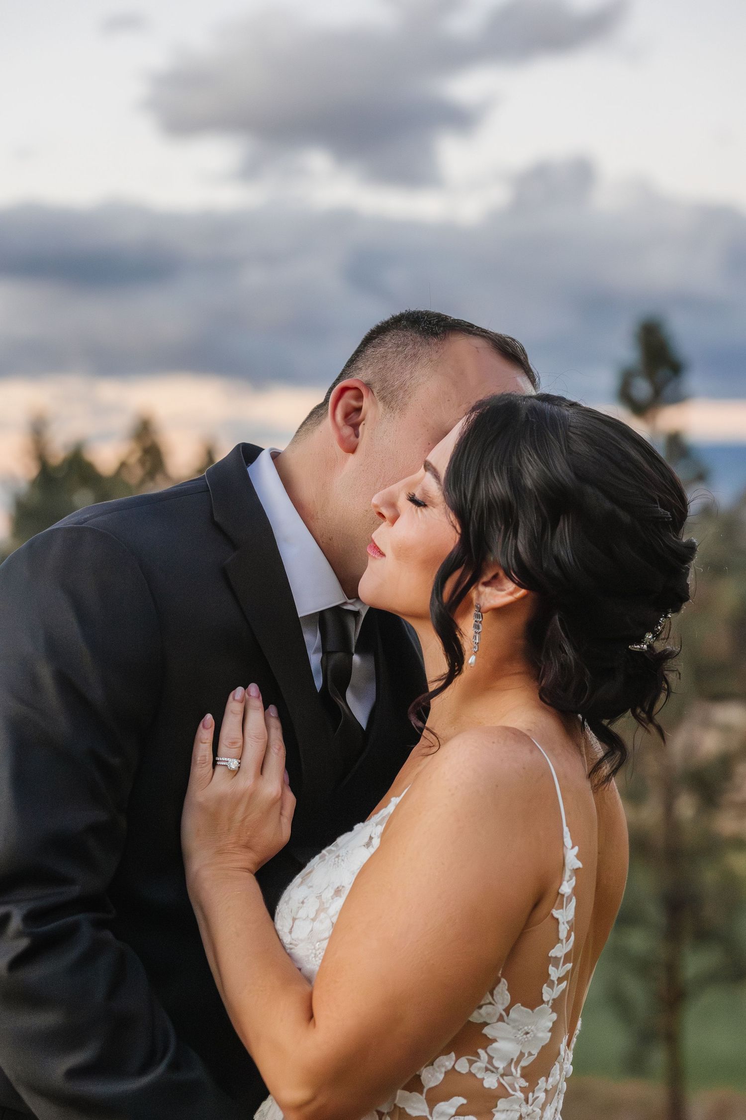 Couple shares intimate romantic moment against scenic mountain backdrop during sunset wedding photoshoot.