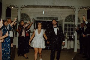 Newlyweds exiting their reception under a shower of sparklers at night.