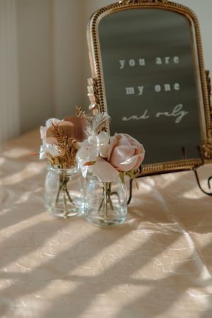 Vintage mirror with 'you are my one' text and soft pink roses in mason jars.
