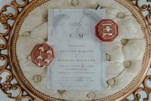 Elegant wedding invitation with wax seals on an ornate gold-rimmed plate.