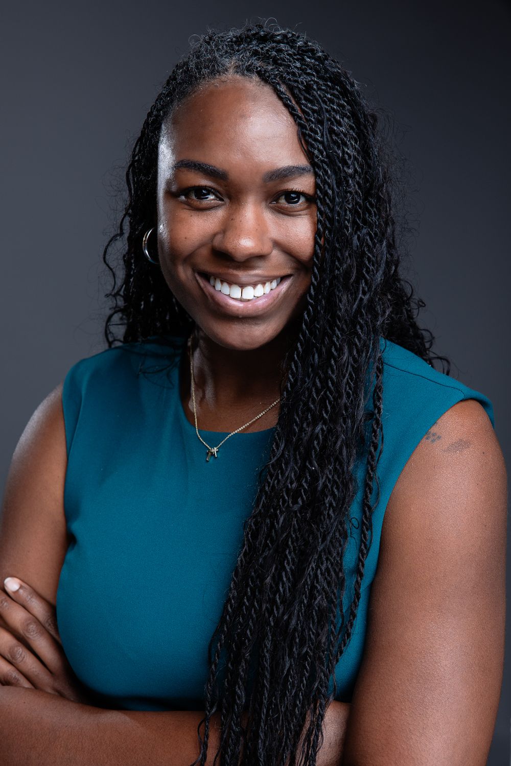 Professional headshot series showing bright smile and long braided hair against dark background wearing teal sleeveless top.