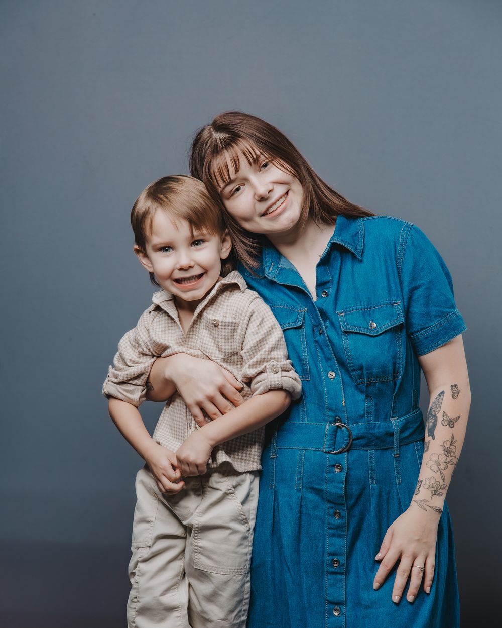 A parent and child share playful moments together against a gray studio backdrop in a series of candid photos.