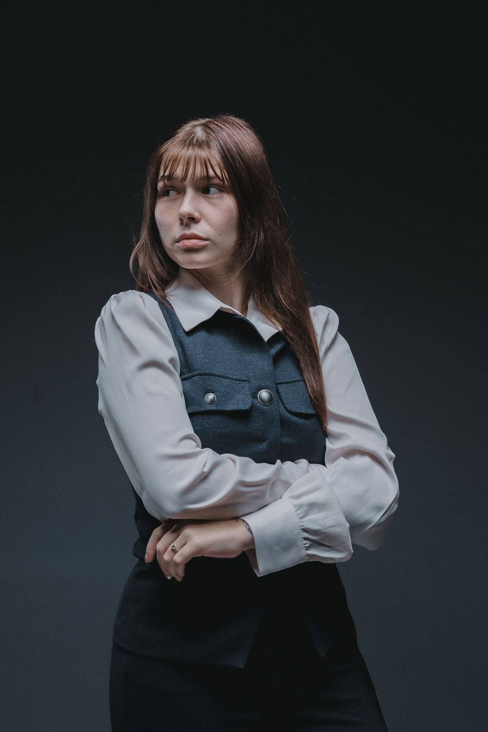 Moody studio fashion photo showing contrasting black vest and white shirt styling.