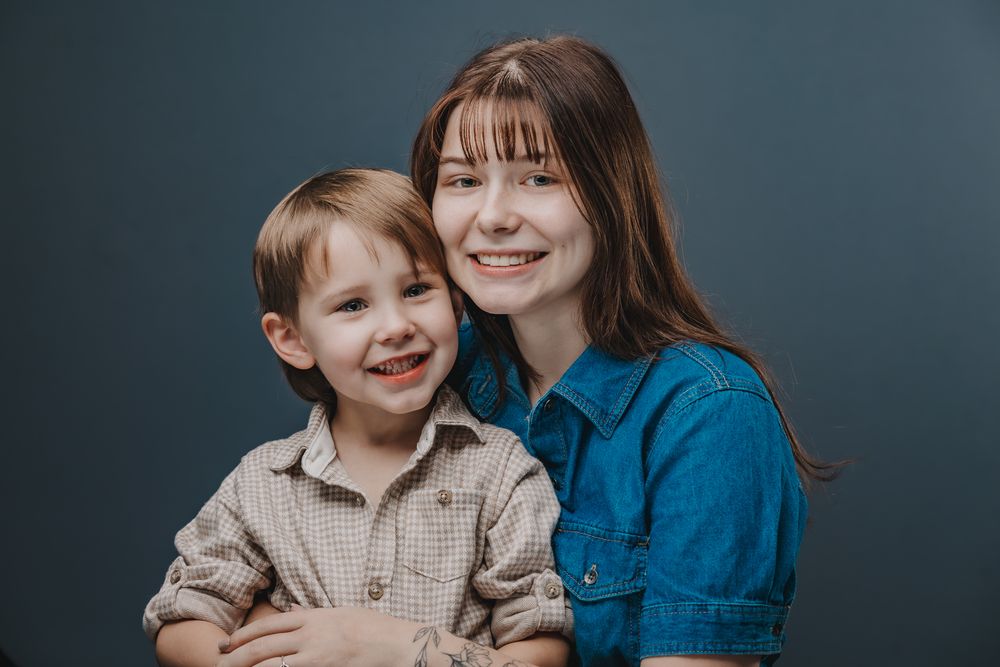 A mother and young son share joyful moments together in a series of candid portraits against a dark background.