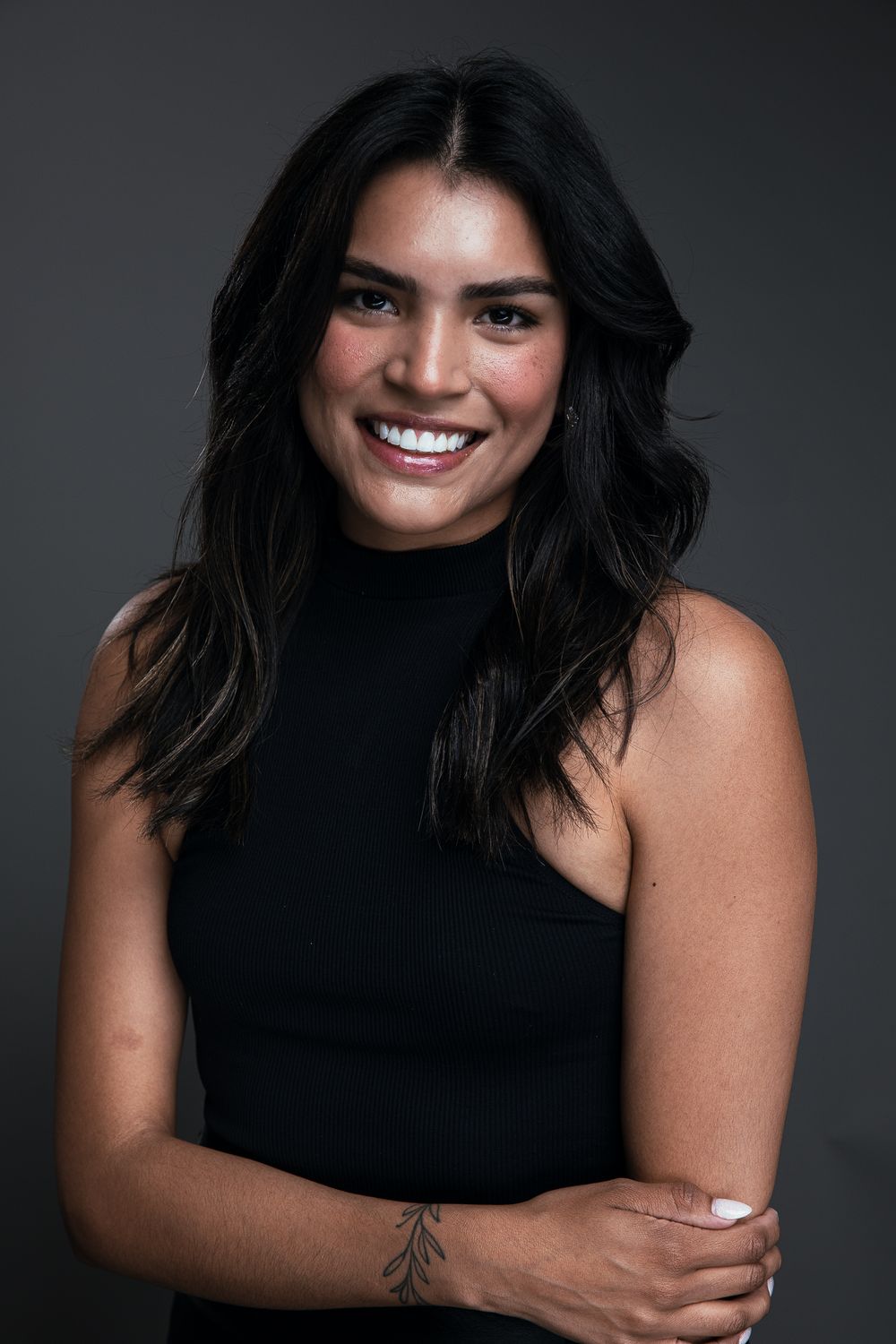 Professional studio portrait series showing joyful expressions against dark background wearing a black sleeveless top.