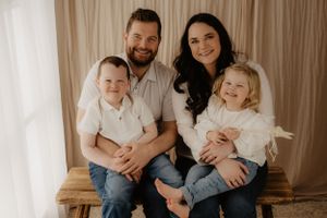 Family portrait with neutral background and coordinated white and denim outfits.
