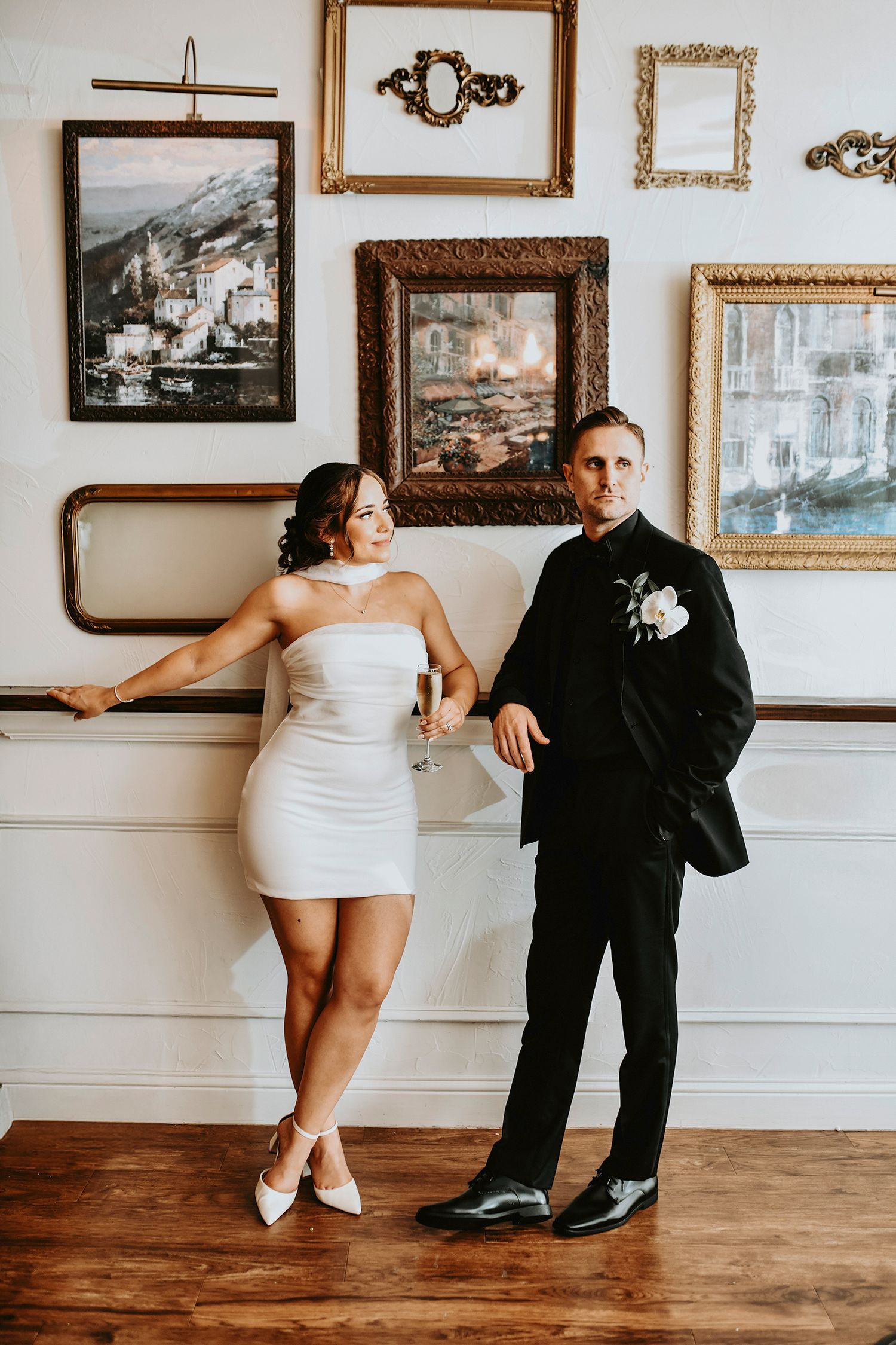 Bride and groom standing together in front of a wall of vintage frames