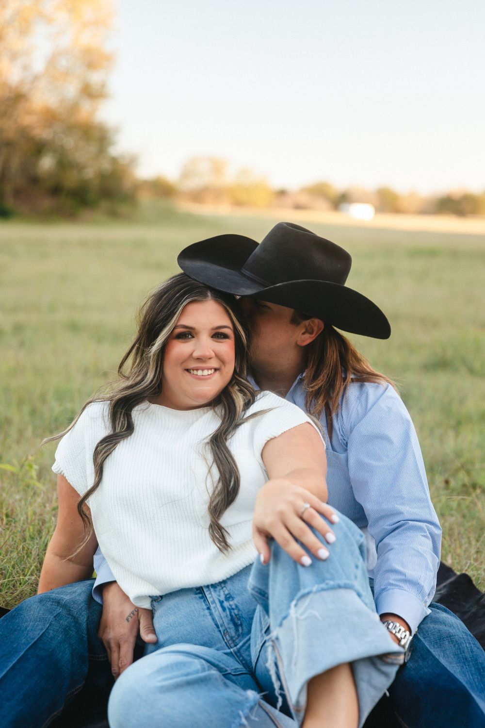 Casual country-style couple photos in a grassy field during golden hour.