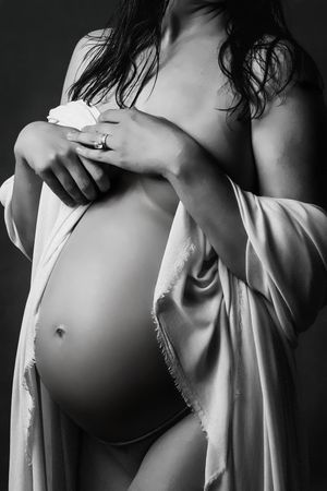 A monochromatic artistic pregnancy photo series showing growing baby bump draped in white fabric across multiple frames.
