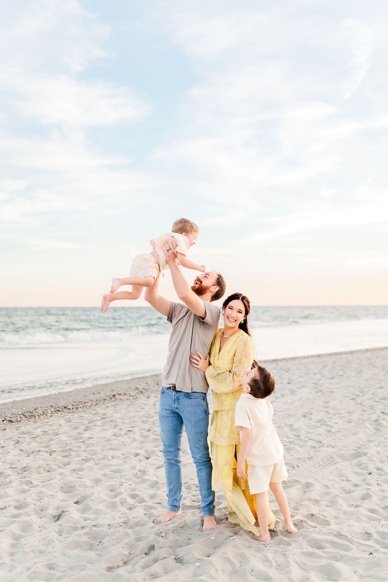 A family shares joyful moments together while playing on a sandy beach at sunset.