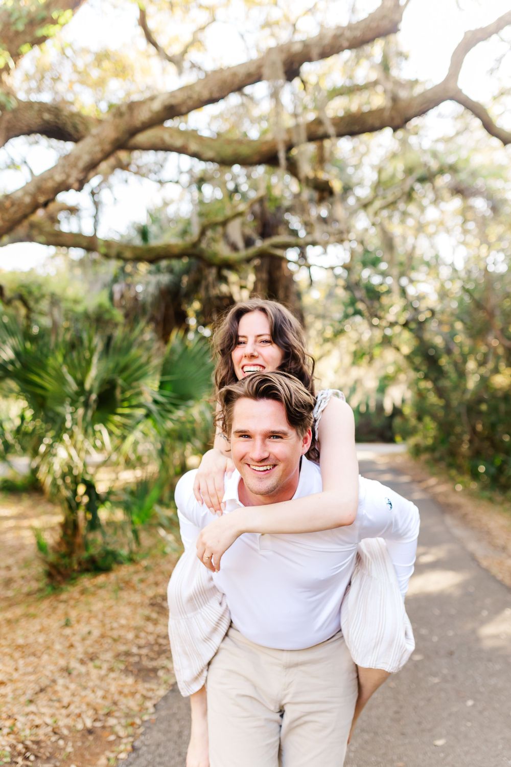 A joyful piggyback ride along a tree-lined path on a bright sunny day.