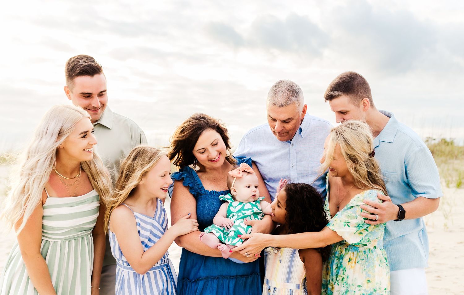 A series of beach family portraits showing groups in coordinated blue and white outfits walking and posing on sandy shores.