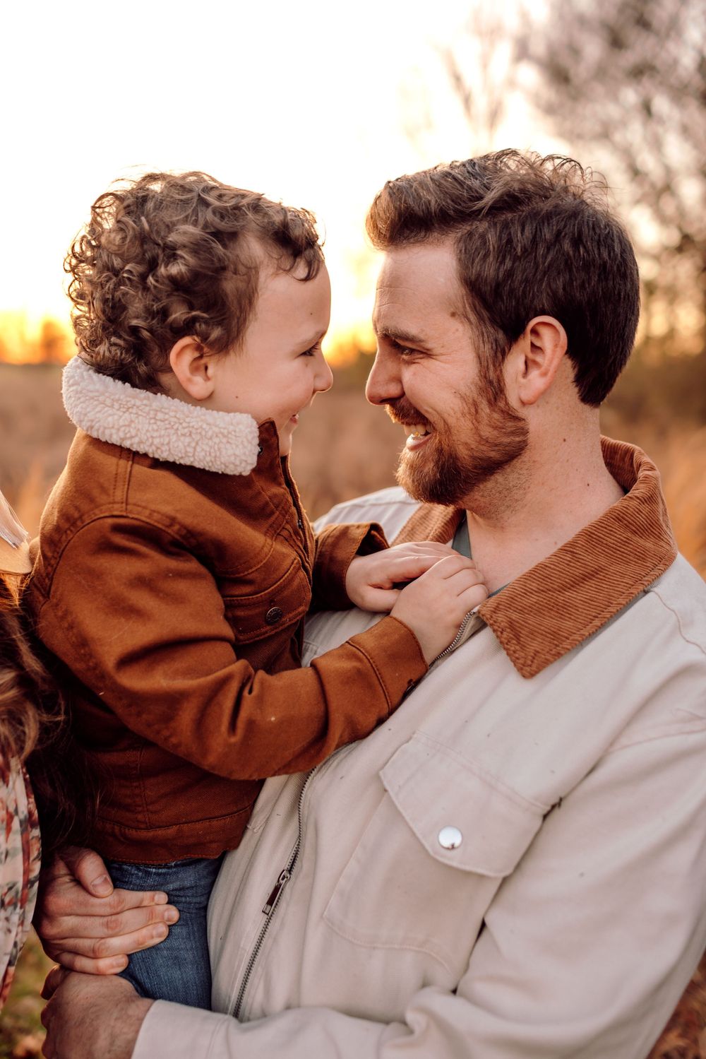 Son and father smiling in arms together during family session in Denver NC