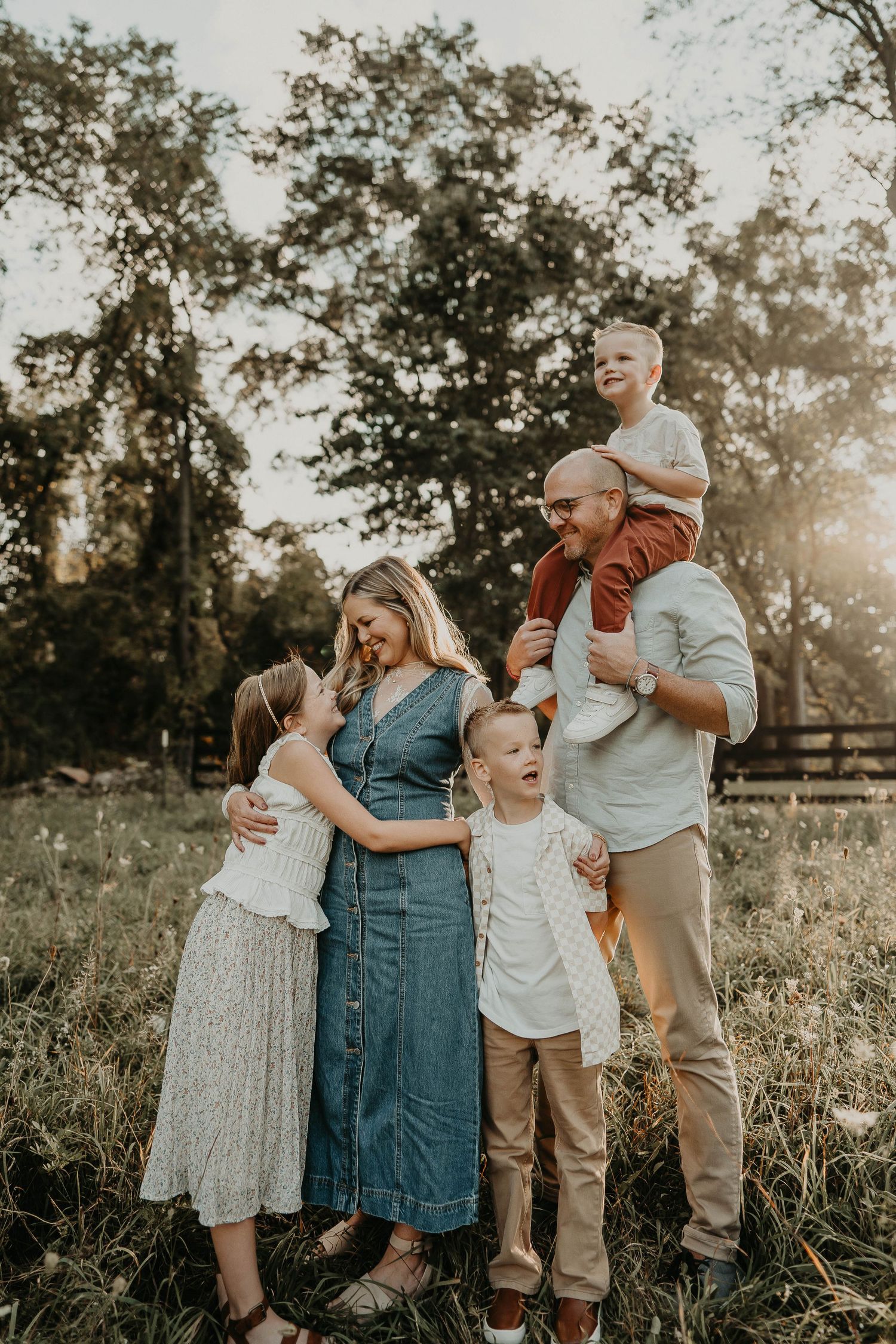 Family of five and dog smiling infant of a white barn
