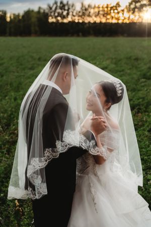An under veil portrait of a bride and groom in a field set against a sunset sky in Albuquerque, New Mexico.
