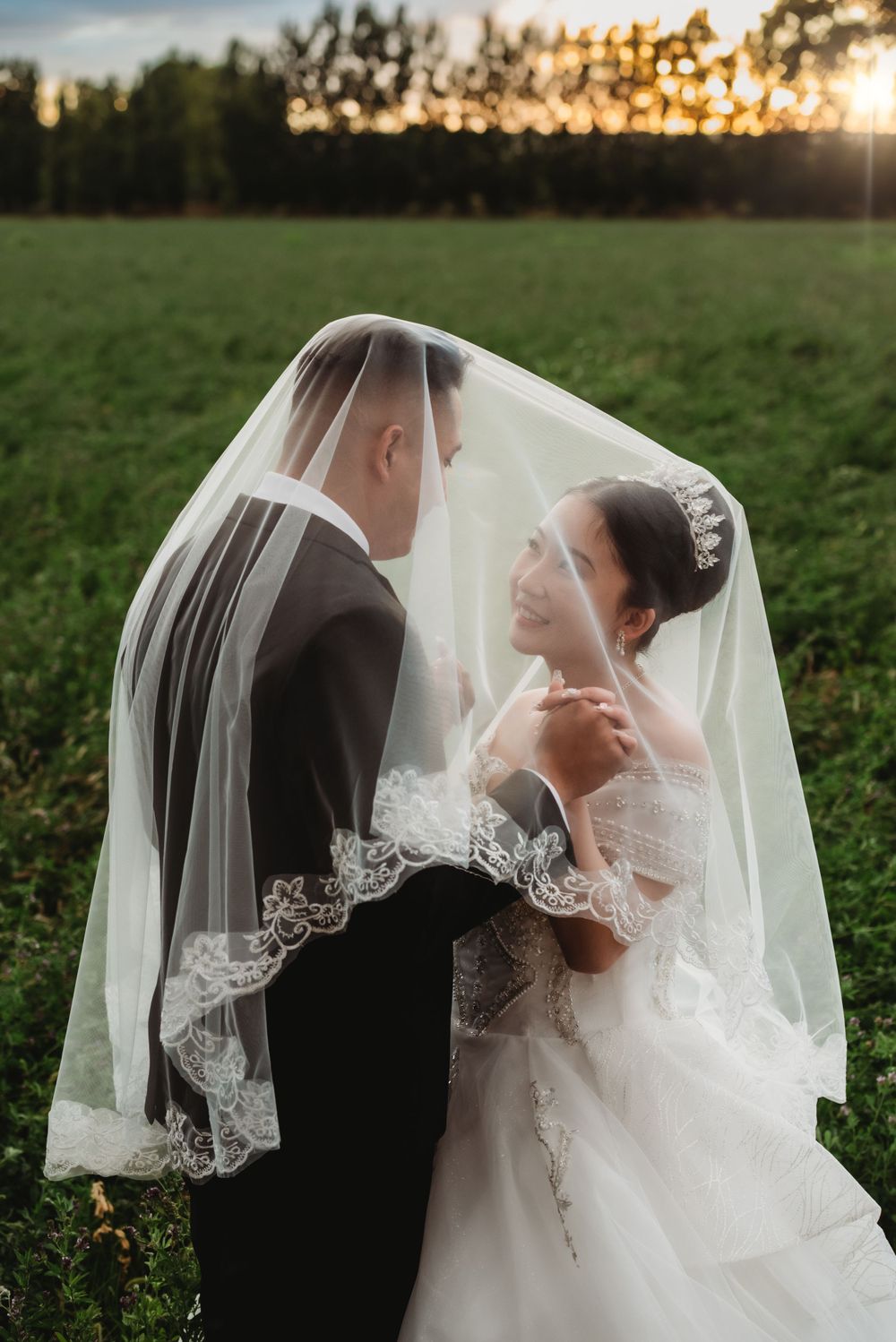An under veil portrait of a bride and groom in a field set against a sunset sky in Albuquerque, New Mexico.