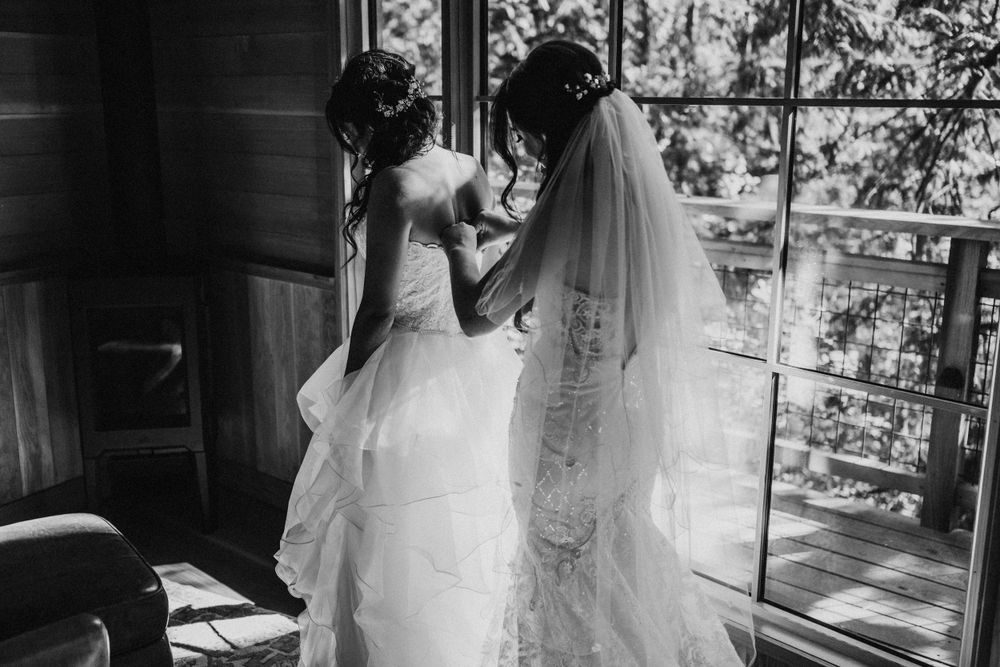 Treehouse elopement in Washington state. Two brides in wedding dresses getting ready in a treehouse.