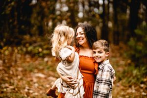 Family group sharing joyful moment together in autumn forest setting.