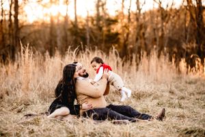 A couple shares a playful moment while lying in golden grass during sunset.